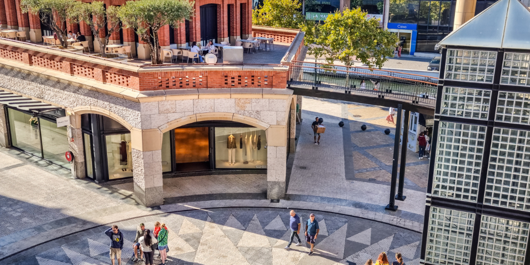 Foto de uma praça pública em Portugal com pessoas andando.