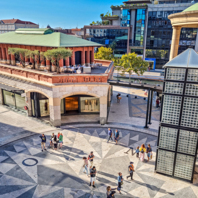 Foto de uma praça pública em Portugal com pessoas andando.